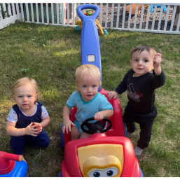 three children playing with a red car
