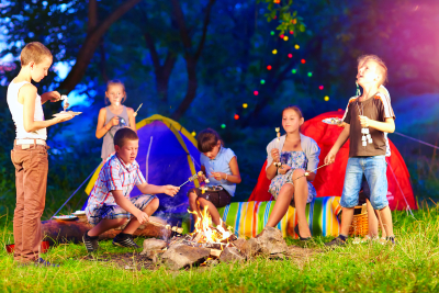 happy kids around bonfire in summer camp